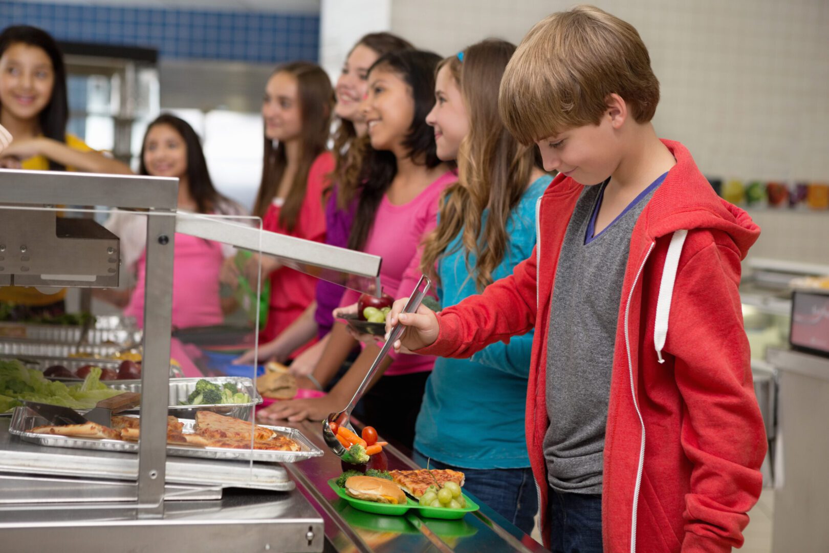 Children serving themselves food in a school cafeteria line.
