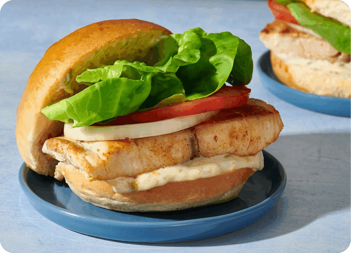 Grilled chicken sandwich with lettuce and tomato on a bun.