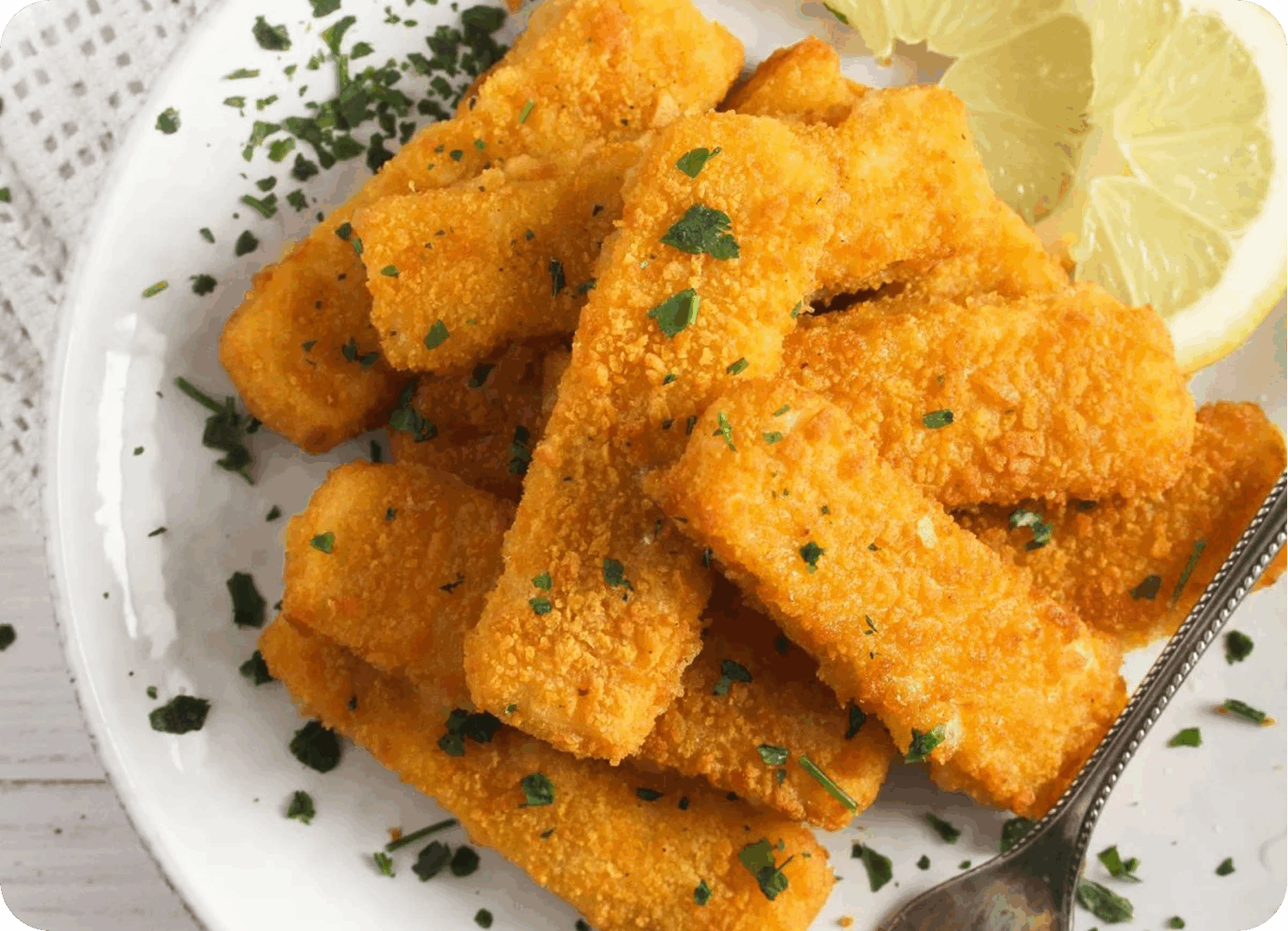 Golden fried fish sticks garnished with parsley and served with a lemon wedge.