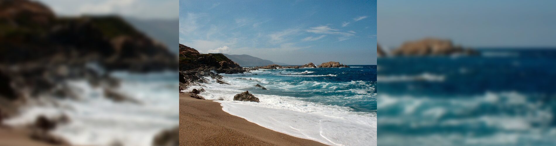 Rocky shoreline with waves crashing under a partly cloudy sky.