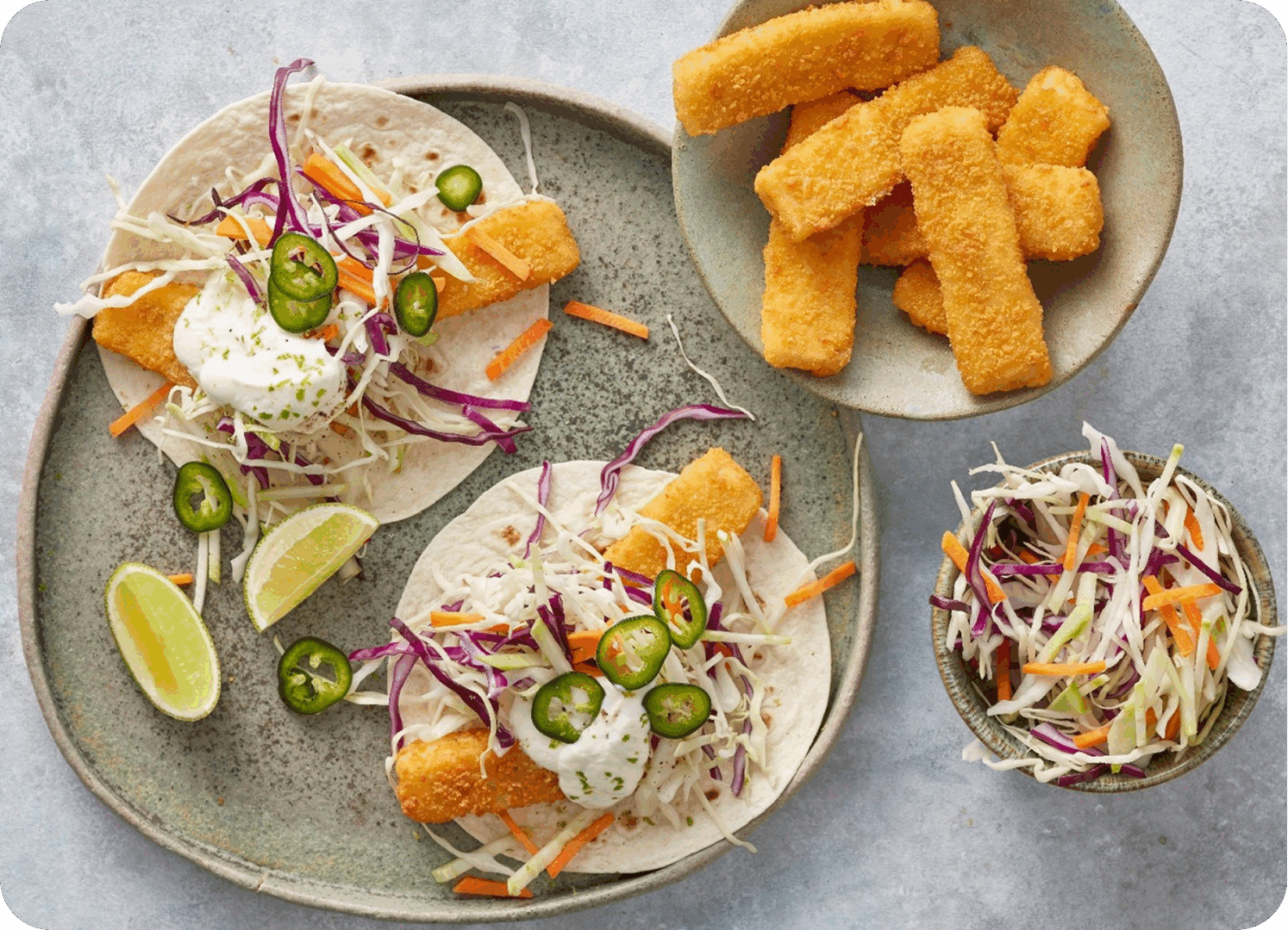 Fish tacos with coleslaw and lime wedges on plates.